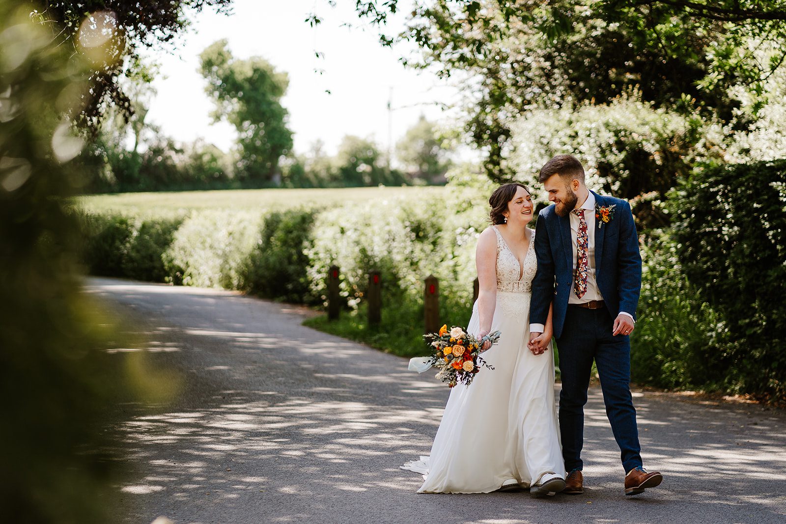 Bride and groom walk along country lane on a sunny wedding day at Larkspur Lodge Wedding vennue in Cheshire