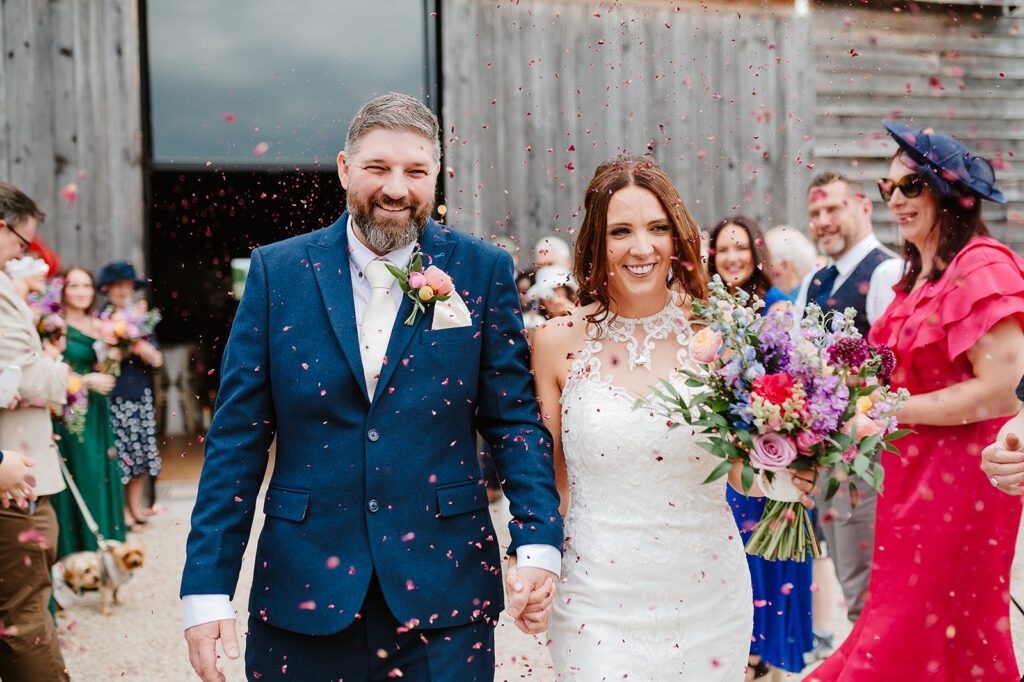 Bride and groom walk through confetti throw at wedding at Stock Farm Barn Cheshire