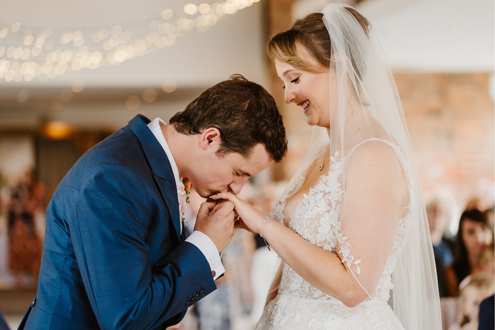 Groom kisses bride's hand after placing wedding ring on finger