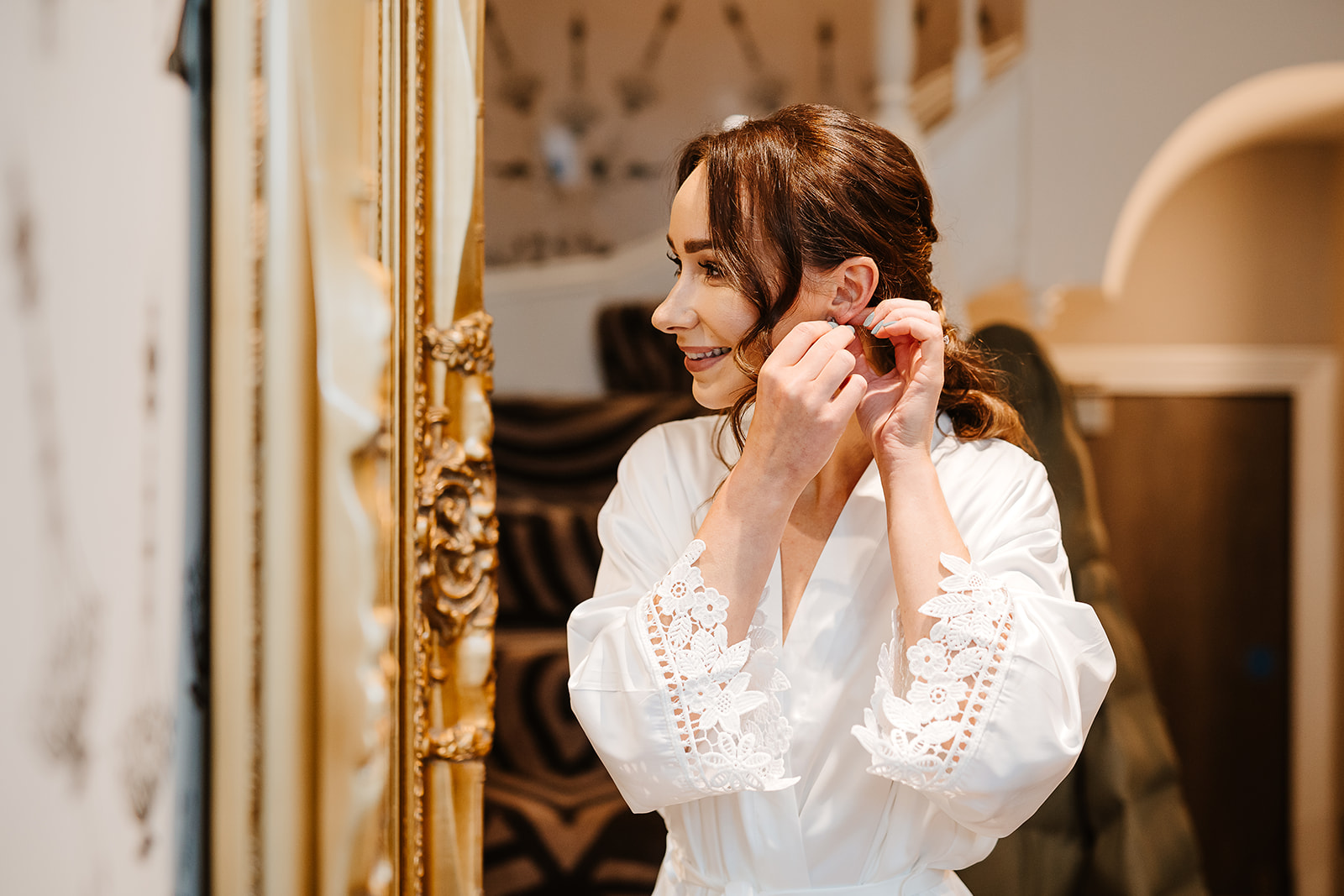 Bride adjusts earrings by mirror