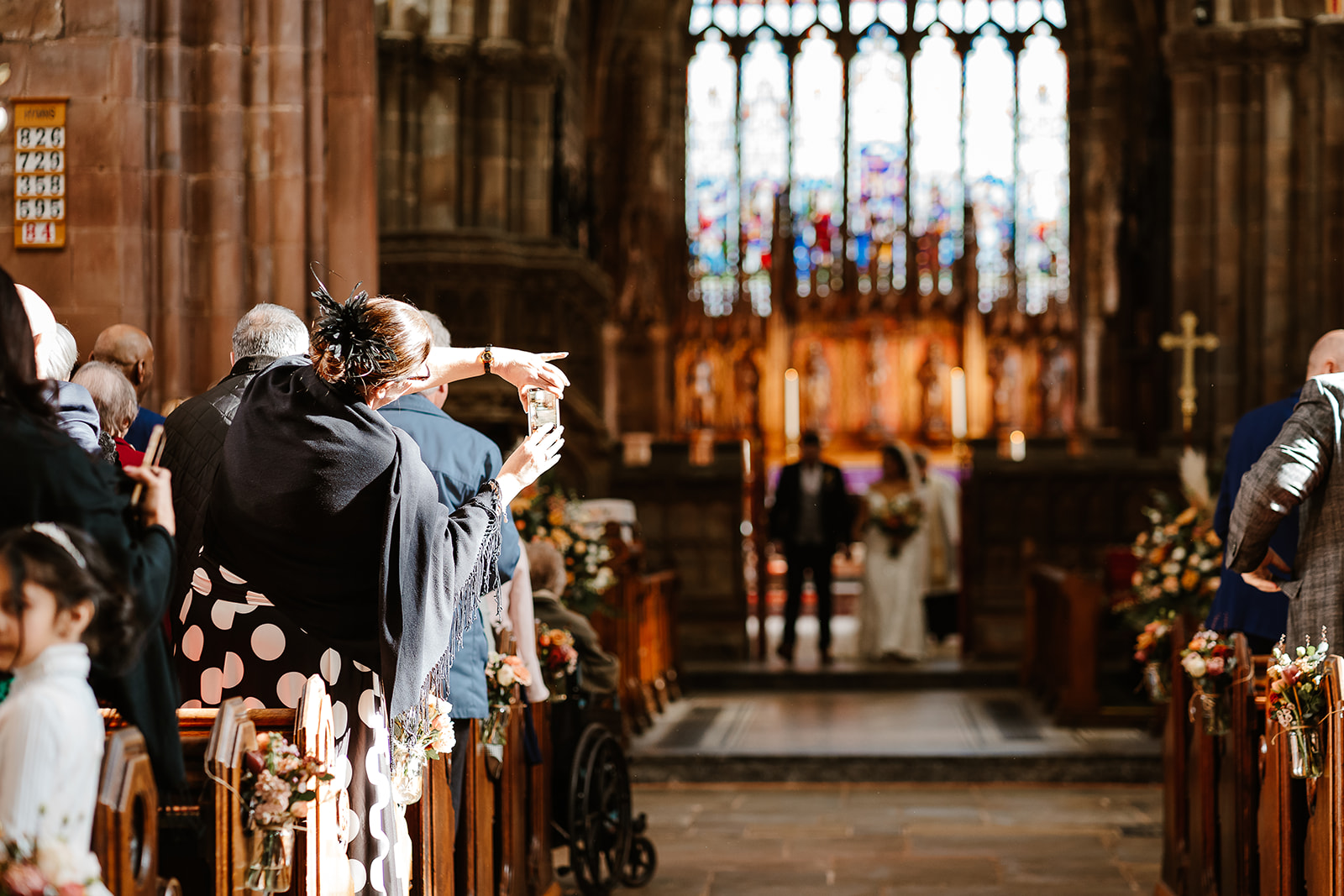 Woman holds mobile phone in church taking photo of bride and groom
