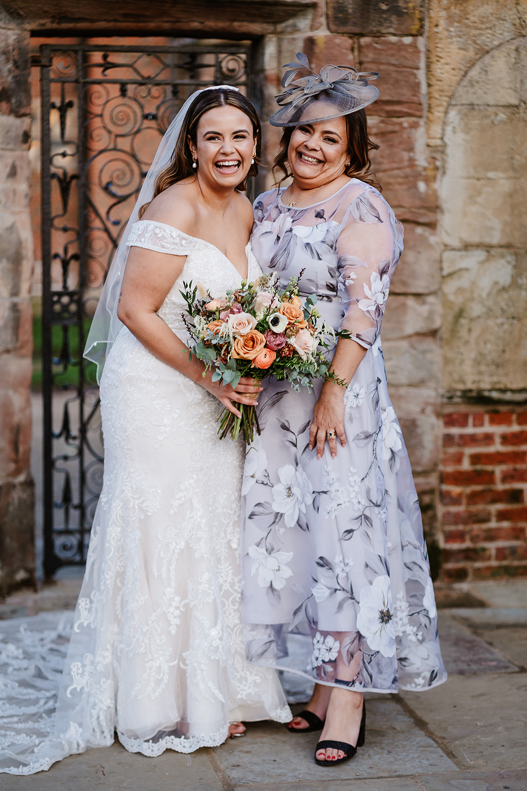 Bride and mother pose in front of ornamental gate