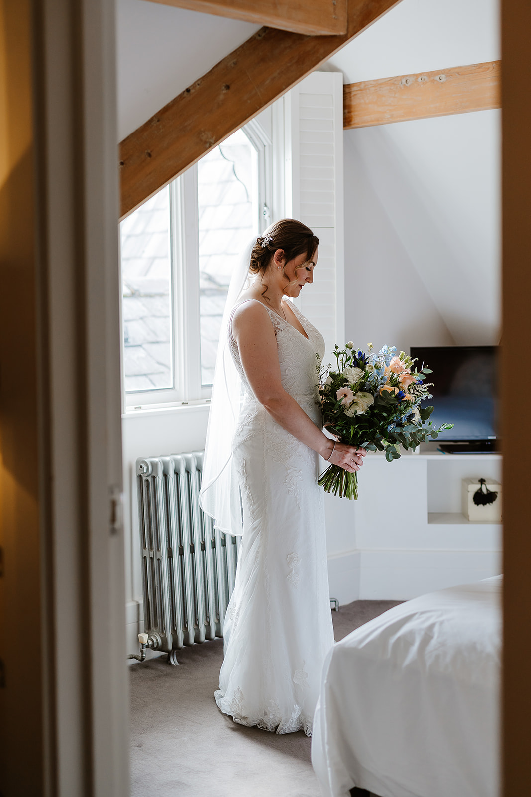 Bride posing with bouquet by window