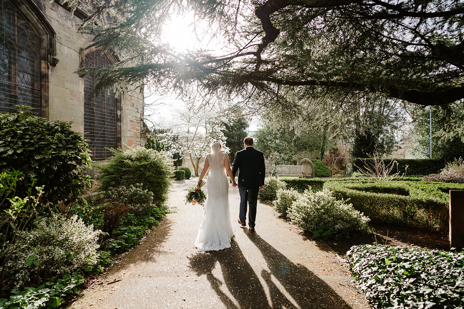 Bride and groom walking under tree with long shadows