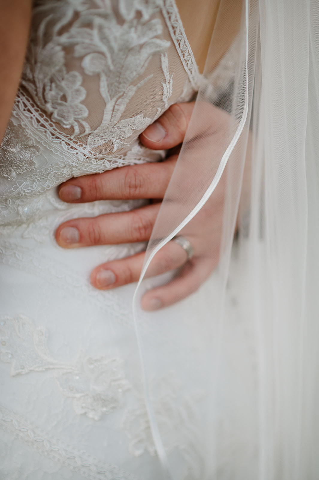 Groom's hand with ring holding waist