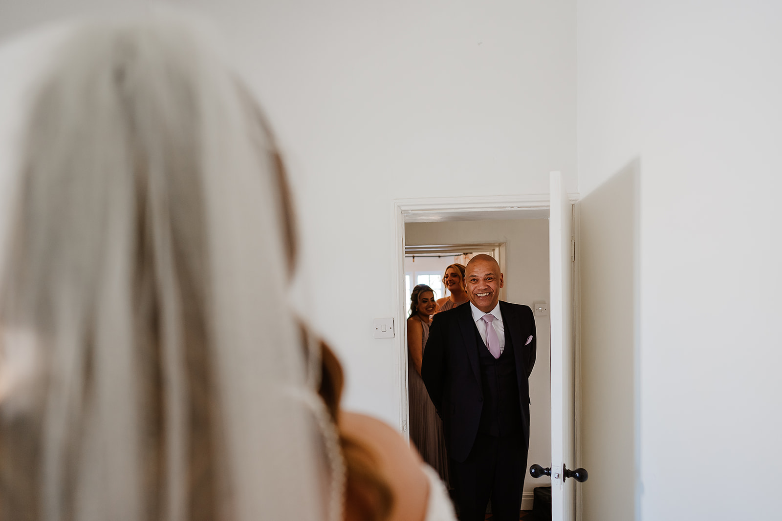 Father of bride emerges through doorway smiling