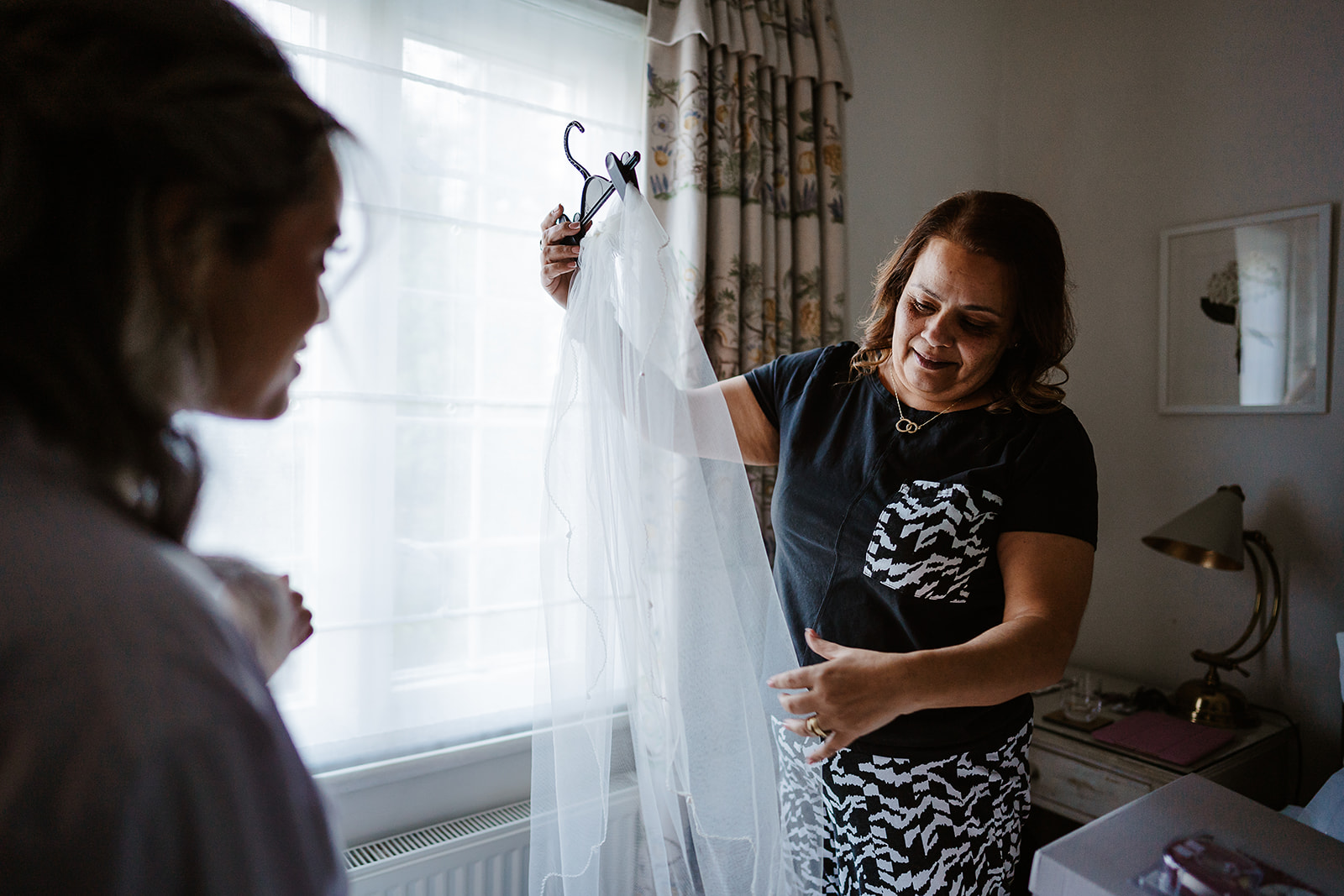 Bride's mother holding veil by window