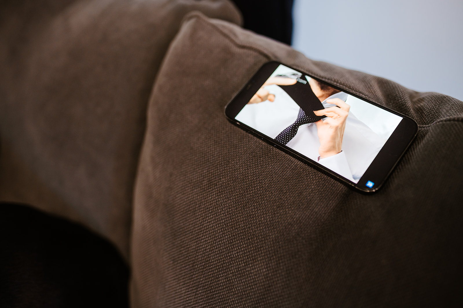 Mobile phone on cushion with video of tie being tied on screen