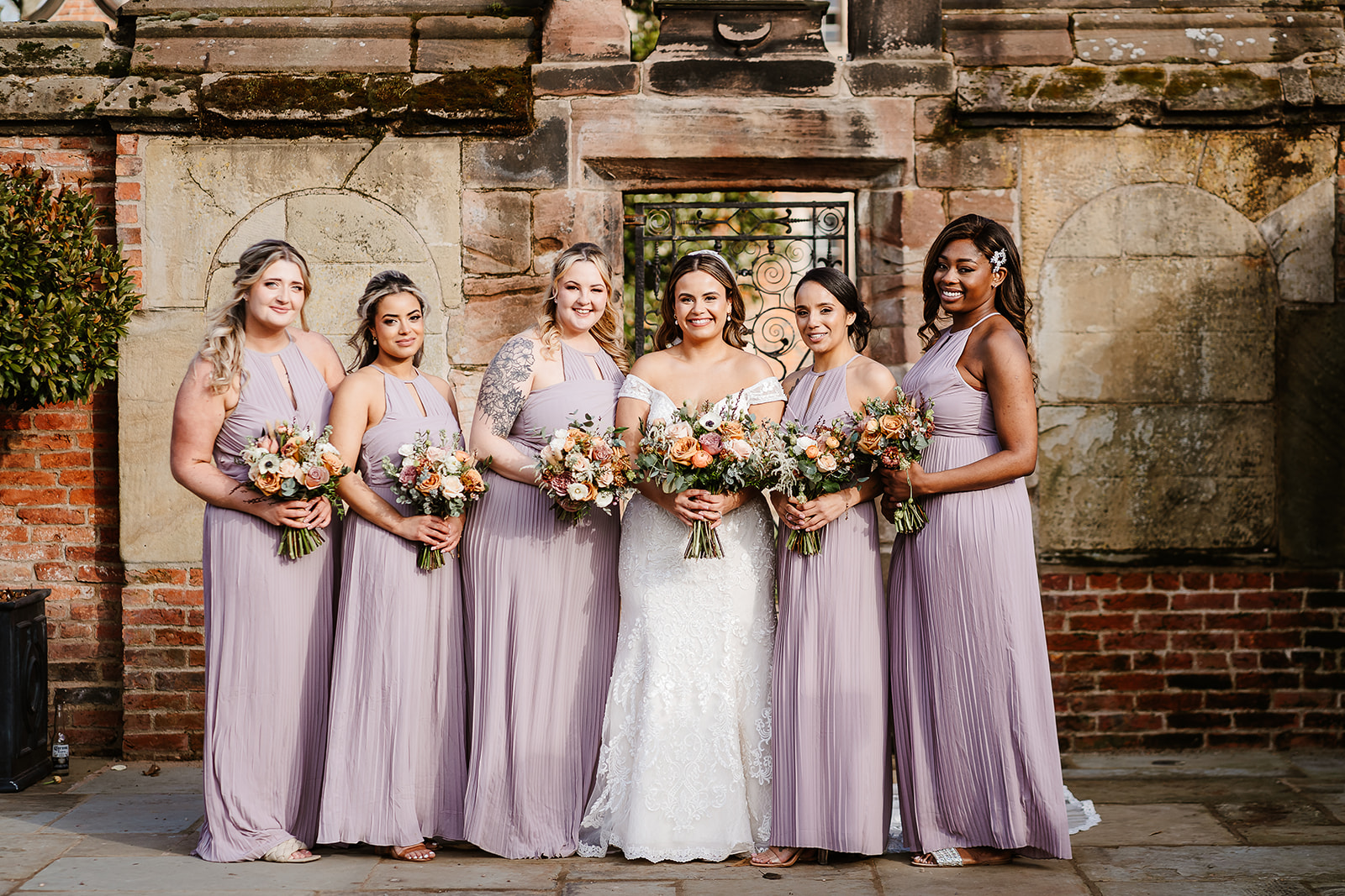 Bride and bridesmaids pose in front of ornate gate