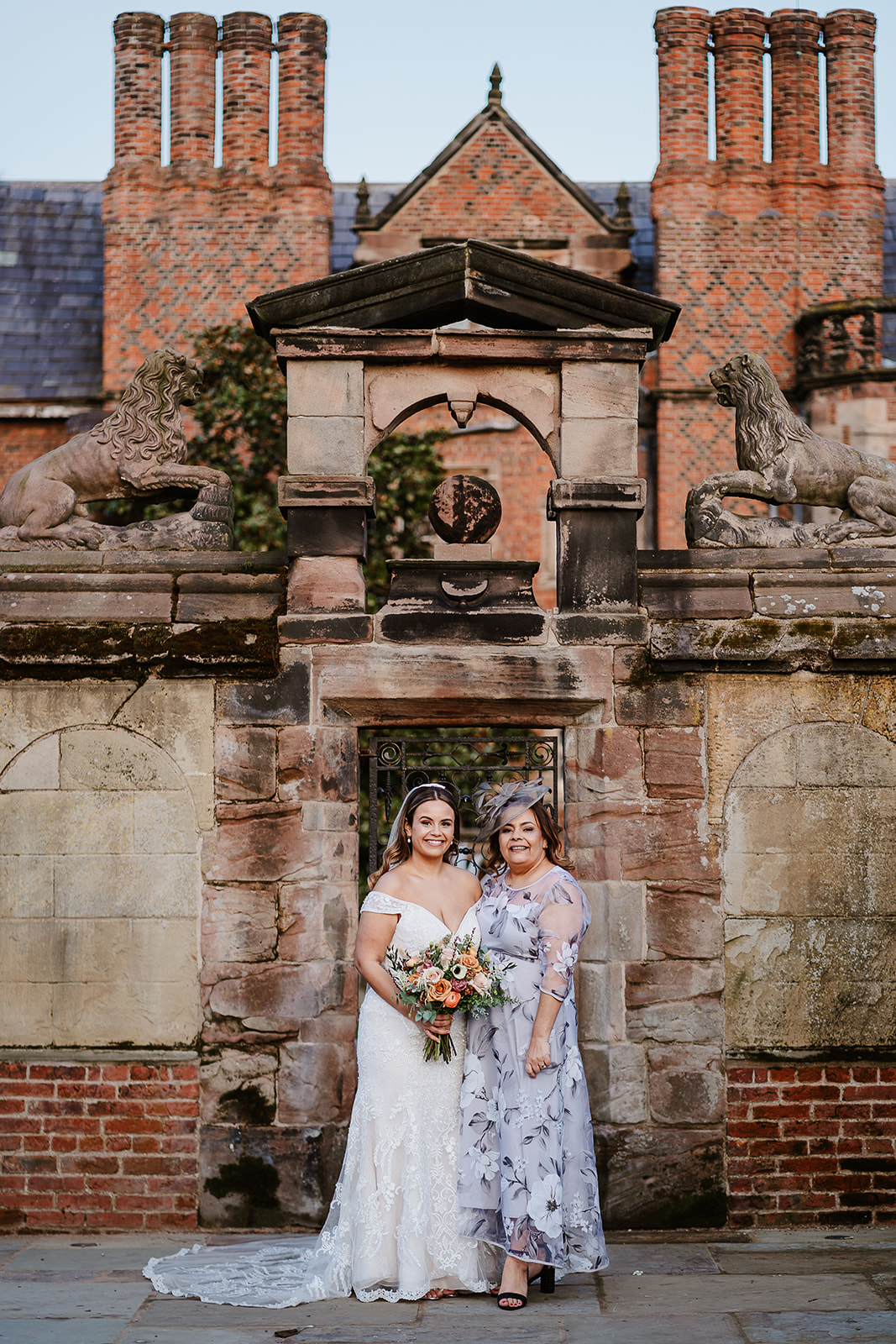 Bride and mother pose in front of ornate gate