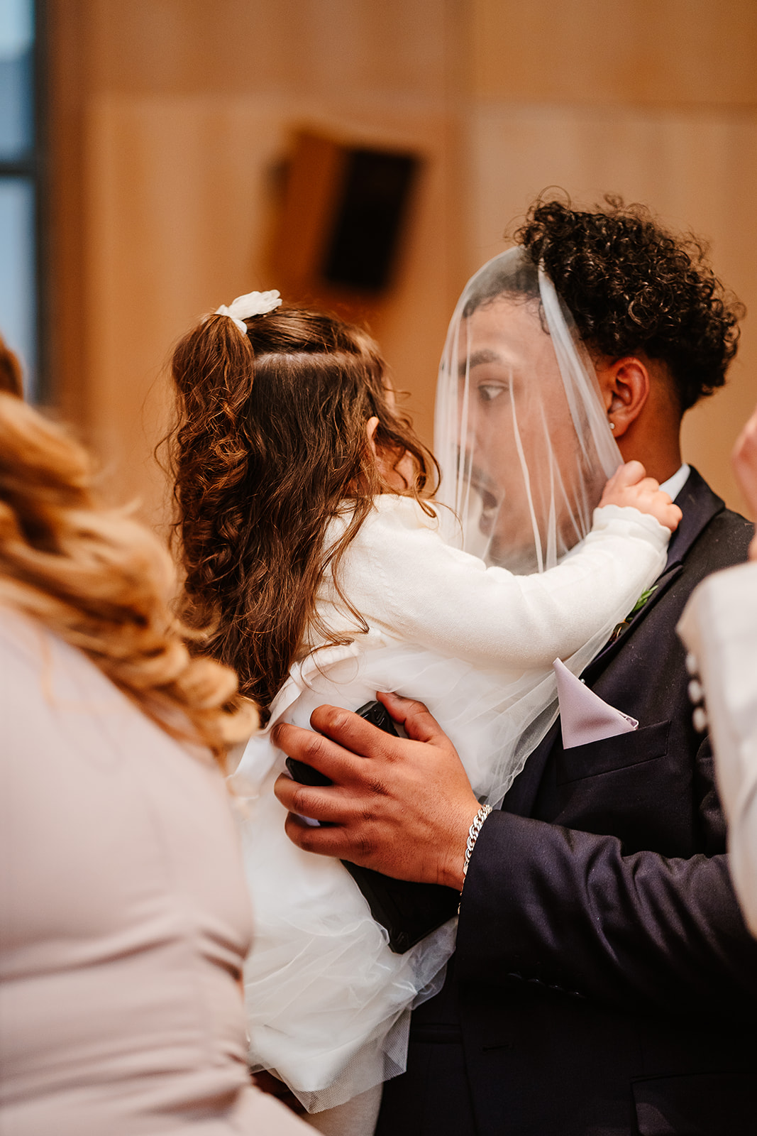 Child holding veil over face of a guest