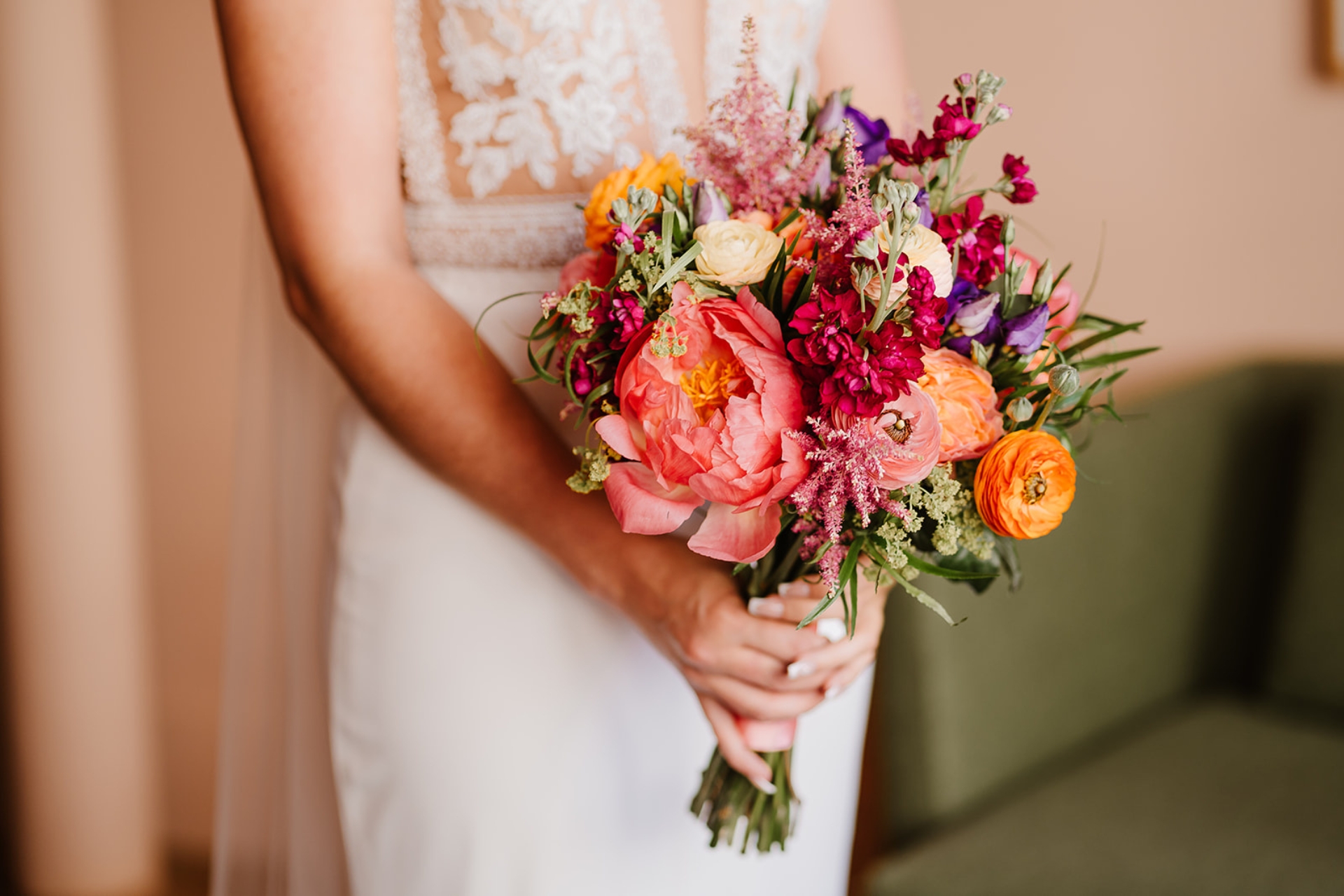 Close up of bridal bouquet of peonies and ranunculus in oranges and pink tones.