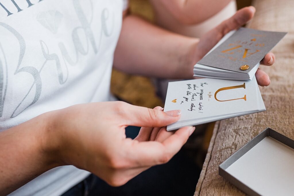 Close-up of bride-to-be's hand as she looks through hand-written note from her husband to be.